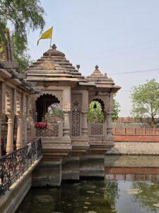 Ornate stone temple structure beside a calm pond