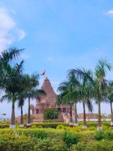 A stunning view of Shree Khodaldham Mandir adorned by blue skies and lush greenery in Rajkot, Gujarat.