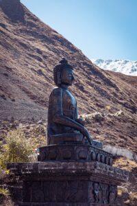 A serene Buddha statue at Muktinath in Nepal, set against a stunning mountainous backdrop.
