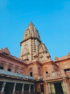 Beautiful view of a historic Hindu temple with intricate architecture and pink façade under a clear blue sky.