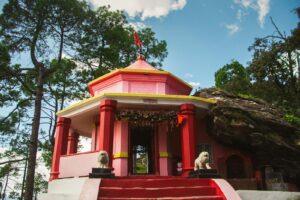 Beautiful Hindu temple amidst pine trees in Binsar, Uttarakhand under a clear sky.
