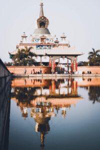 A tranquil view of a traditional temple in Lumbini, Nepal, reflecting in a calm lake.